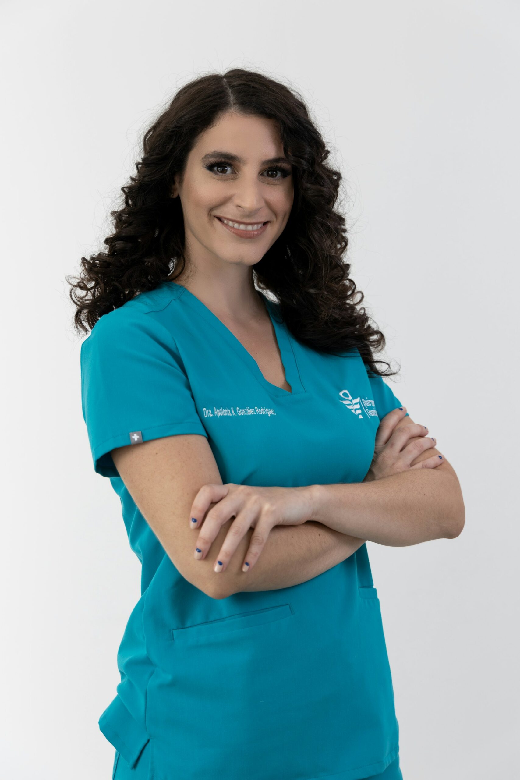 Smiling nurse in teal scrubs with arms crossed