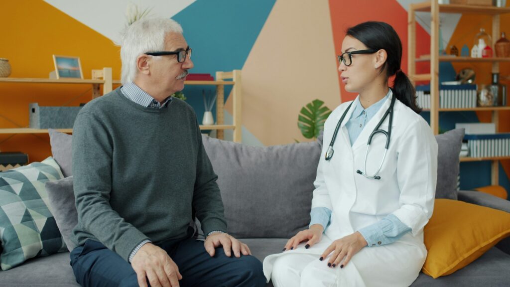 Clinician talking with an older patient on a sofa